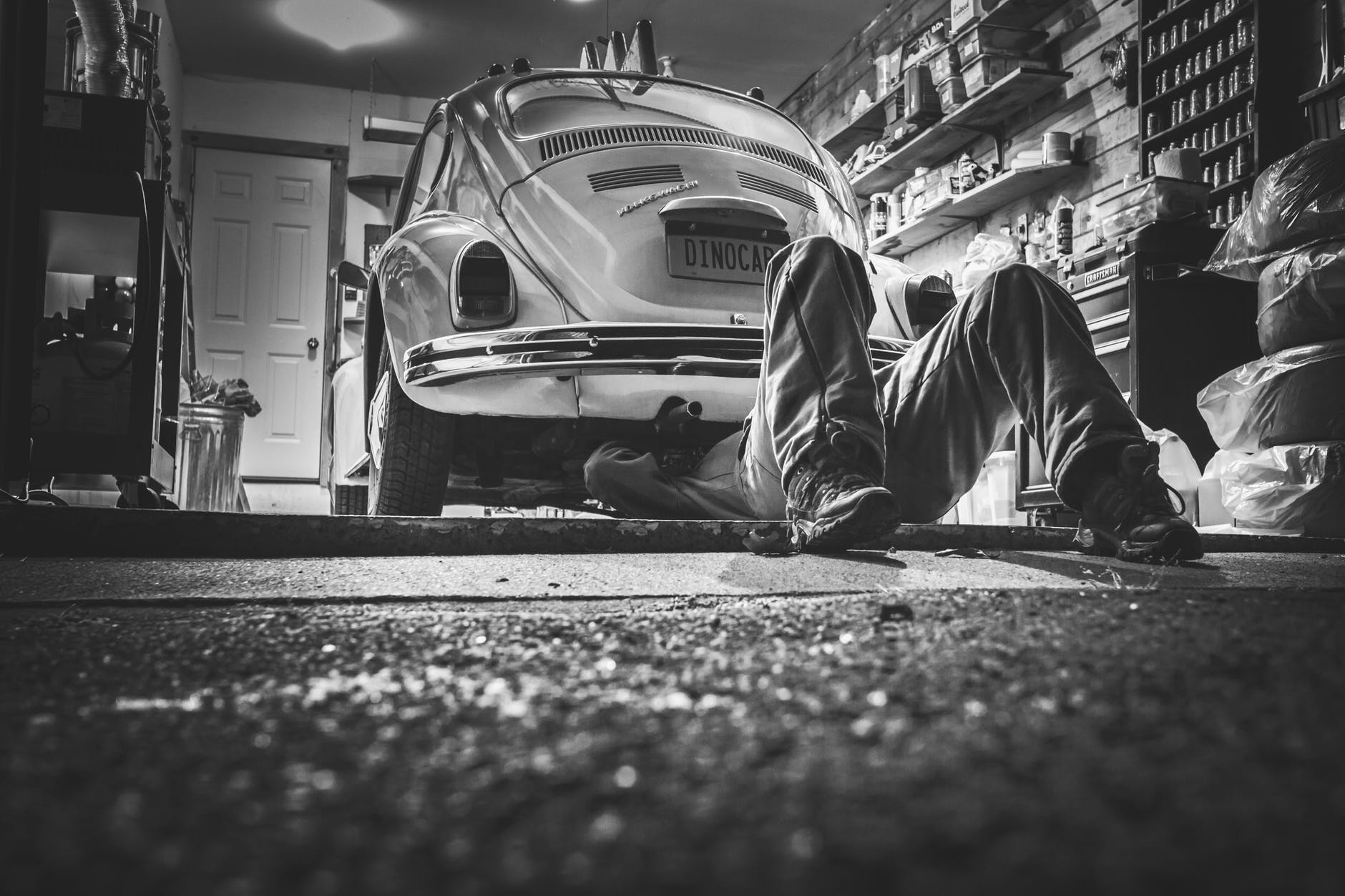 Black & White photo of man working under Dinocar