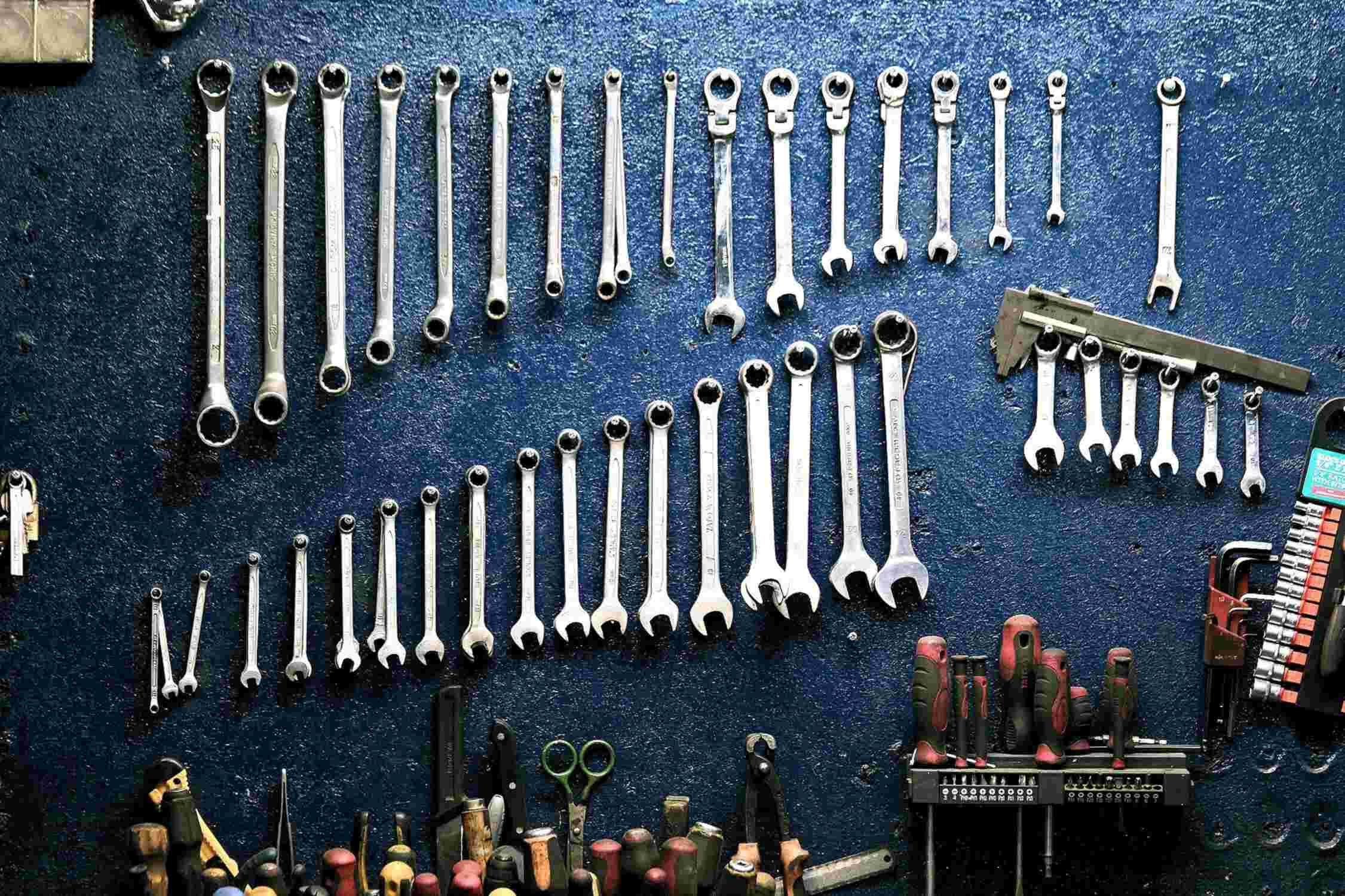 Wrenches of various sizes on blue wall