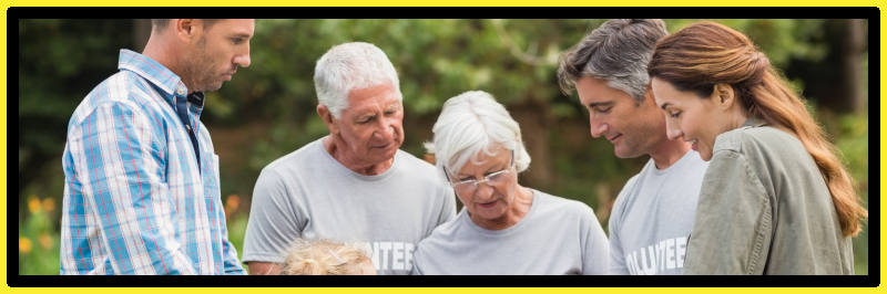 Elderly volunteers stood with two charity trustees who are discussing fundraising plans. 