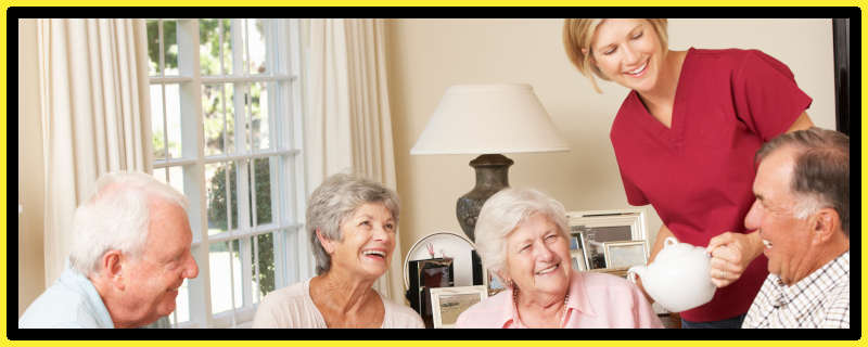 Worker serving tea to elderly people as they laugh