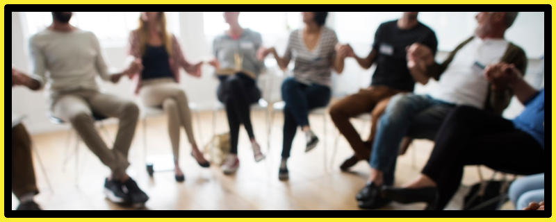 Community group sit in a circle holding hands